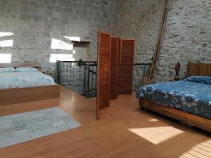 a bedroom with two beds and a stone wall at LE LOFT in Casteljaloux