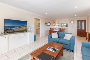 a living room with a blue couch and a tv at Surfspray 3 Pebbly Beach in Forster