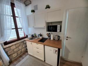 a kitchen with white cabinets and a sink and a microwave at Placeta Apartments in Dubrovnik
