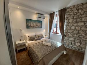 sypialnia z łóżkiem i kamienną ścianą w obiekcie Placeta Apartments w Dubrowniku