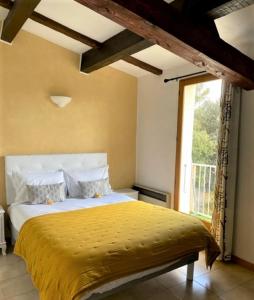 um quarto com uma cama com um edredão amarelo e uma janela em auberge du castellas em Sainte-Croix-de-Verdon