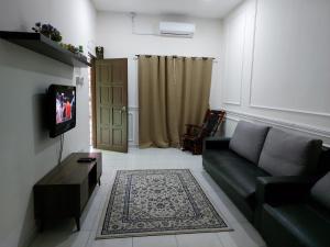 a living room with a couch and a television at Pelangi homestay in Kampung Bota Kiri +5 photos