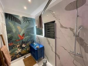 ein Bad mit einer Dusche mit einem Wandbild aus Fisch in der Unterkunft Villa Prana in La Saline-Les-Bains