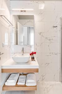 La salle de bains blanche est pourvue d'un lavabo et d'un miroir. dans l'établissement Lumiére spetses, à Spetses 37 autres photos