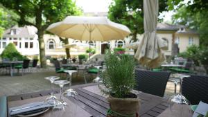 ein Holztisch mit einem Regenschirm und einigen Stühlen in der Unterkunft Ringhotel Waldhotel Heiligenhaus in Heiligenhaus