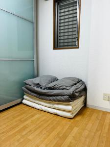 a stack of blankets in a room with a window at Awaza House 1 in Osaka