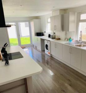 a kitchen with white cabinets and a wooden floor at Barry Townhouse in Barry