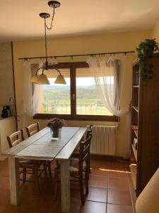 a dining room table with chairs and a large window at La Casa de Baix in Torre del Compte