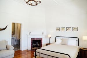 a white bedroom with a bed and a fireplace at Mount William Station in Willaura