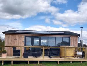 a tiny house with a solar roof on a deck at Cleeves Cabins Ailsa Lodge with hot tub luxury in Dalry