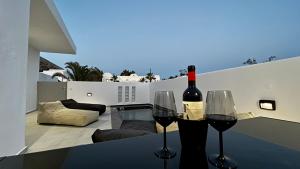 a bottle of wine and two glasses on a table at Filoxenia Luxury Villas in Perissa