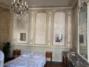 um quarto com uma cama, uma mesa e um lustre em Hôtel du marquis De Broc em Le Mans