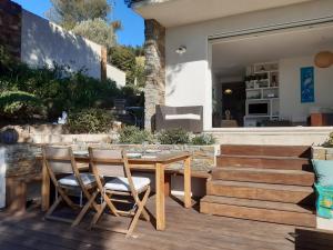 una mesa de madera y sillas en una terraza de madera en VILLA ANADINE - Aiguebonne BOULOURIS - PLEINE VUE MER - À 5 minutes à pied de la plage - Climatisée, en Saint-Raphaël