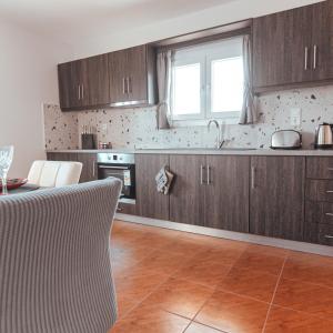 kuchnia z drewnianymi szafkami, stołem i oknem w obiekcie Home Sweet Home Prevezas w Prewezie