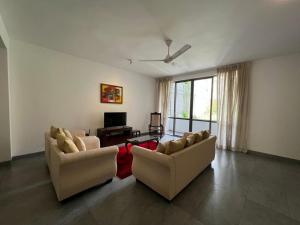 a living room with two couches and a tv at VIBE Hostels in Colombo