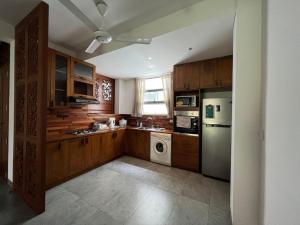 a kitchen with wooden cabinets and a washer and dryer at VIBE Colombo in Colombo