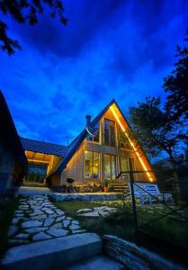 a house with lights on the side of it at night at Pine Cabins Zlatibor in Zlatibor