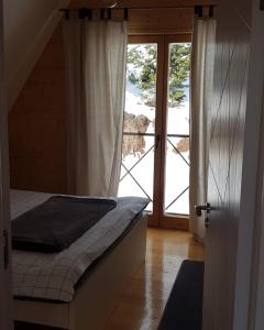 a bedroom with a bed and a sliding glass door at Pine Cabins Zlatibor in Zlatibor