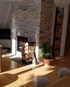 Pine Cabins Zlatibor في زلاتيبور: غرفة معيشة مع موقد حجري مع كرسي