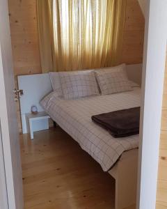 ein kleines Bett in einem Zimmer mit Fenster in der Unterkunft Pine Cabins Zlatibor in Zlatibor