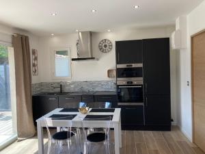 a kitchen with black appliances and a table with stools at Villa Célina Accessible PMR in Sanary-sur-Mer