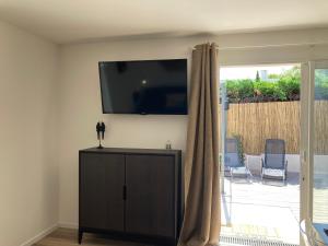 een woonkamer met een flatscreen-tv aan de muur bij Villa Célina Accessible PMR in Sanary-sur-Mer