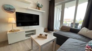 een woonkamer met een bank en een flatscreen-tv bij Ferienwohnung Nordseebrandung A1.4 in Sahlenburg
