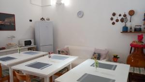 a kitchen with two white tables and a refrigerator at La casa di Mela in Leverano