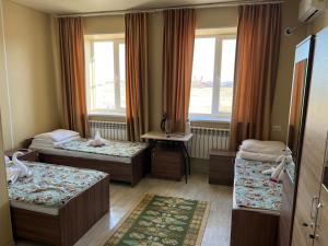 um quarto de hotel com três camas e uma janela em Bereke em Tengiz