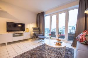 a living room with a couch and a tv and some windows at Marina View in Cuxhaven