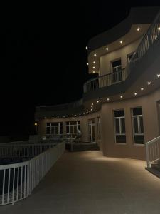 un bâtiment la nuit avec une personne assise sur le balcon dans l'établissement Ocean Chalet, à Salalah