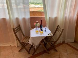 una mesa con 2 sillas, botellas de vino y copas en Vento di Mare, en Muravera