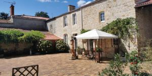 a courtyard with a white umbrella and a building at L'Heureux Lay in La Réorthe