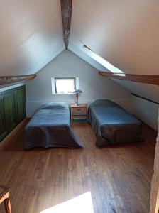 - une chambre mansardée avec 2 lits et une fenêtre dans l'établissement Maison de tout vent, à Pierrefonds