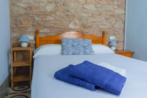 um quarto com uma cama branca com almofadas azuis em Masia Rural Canalisos em Adzaneta