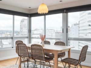 una sala da pranzo con tavolo, sedie e finestre di housingcoruña JUAN FLOREZ a La Coruña
