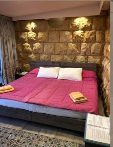 a bedroom with a pink bed with a stone wall at Beit Wadih in Ghazīr