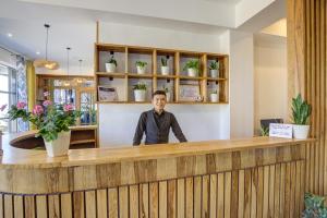 博斯特里Olimp Hotel的站在沙龙木柜台后面的人