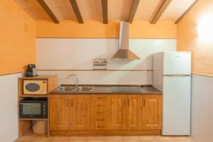 een keuken met een witte koelkast en een magnetron bij Masia Rural Canalisos in Adzaneta