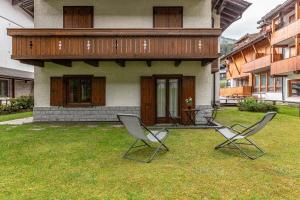 two chairs sitting in the grass in front of a house at Villetta Campiglio in Madonna di Campiglio
