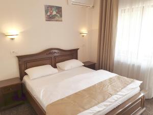 a bedroom with a bed with white sheets and a window at Vila Tisa in Tismana