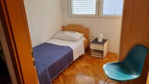 um pequeno quarto com uma cama e uma cadeira azul em Duplex Apartment Promajna em Promajna