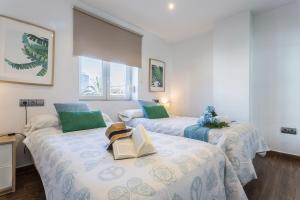2 camas en una habitación con almohadas verdes y un libro en Brisas Playa 3 Baños, en Cádiz