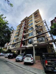 un edificio alto con coches estacionados frente a él en 552 Residence, en Bangkok