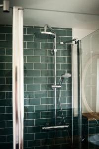 a shower in a bathroom with a green tile wall at Gasthaus Canow in Wustrow