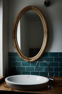 a bathroom with a large oval mirror and a tub at Gasthaus Canow in Wustrow