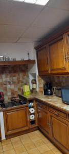 a kitchen with wooden cabinets and a stove top oven at propriété familiale MERLE proche PARAY LE MONIAL in Vauban