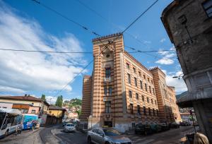 a tall brick building with a clock tower on a street at Old Town Design Apartments in Sarajevo