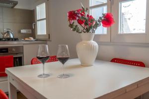 deux verres à vin et un vase avec des fleurs rouges sur une table dans l'établissement 32 nero - Florence Apartment San Niccolò, à Florence