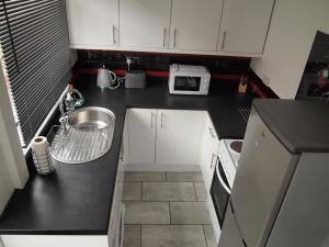 a small kitchen with white cabinets and a sink at Hello Middlesbrough in Middlesbrough